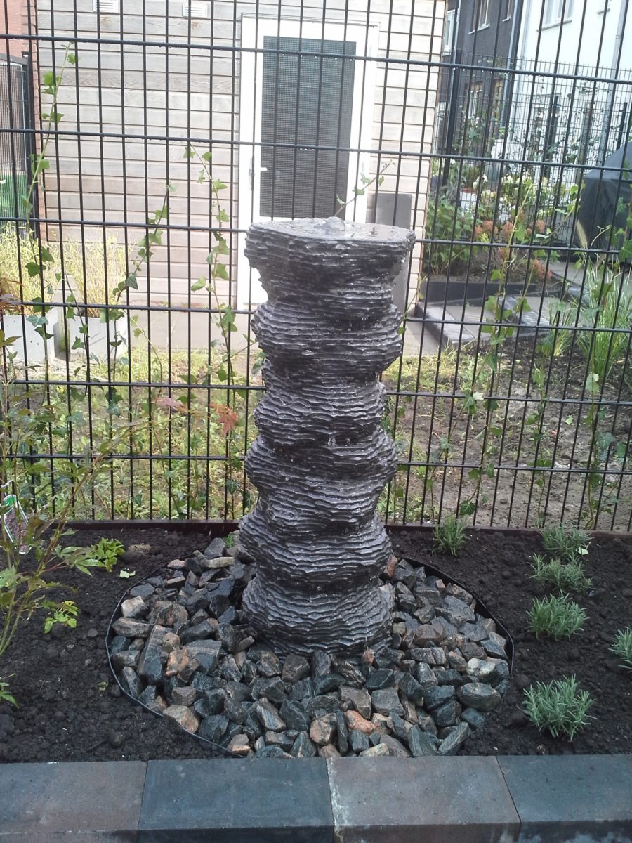 Modern waterornament van natuursteen waar water rustig overheen kabbelt in een grindbed